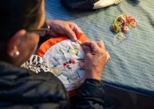 A person does embroidery at DoucheFLUX